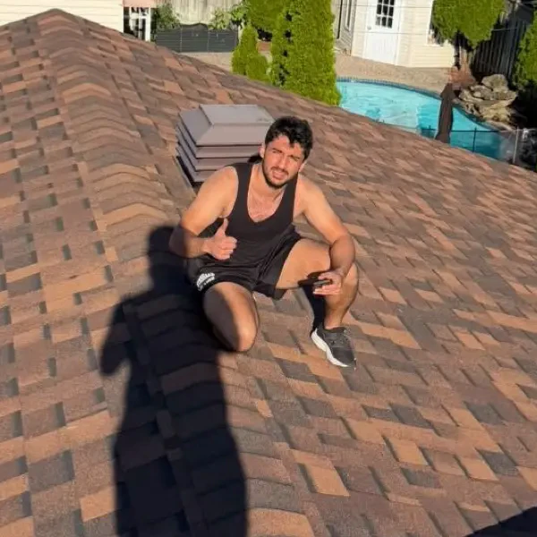 Vyom, Closlyo's founder, crouching on a shingle roof and giving a thumbs up